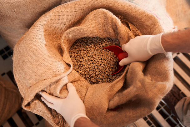 Worker standing near bags with coffee beans - Фото, зображення