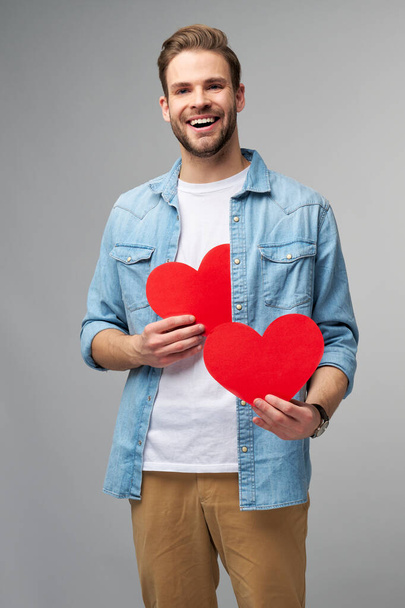 Portret uroczego mężczyzny trzymać rękę papieru w kształcie serca karty nosić casual styl koszuli izolowane na szarym tle - Zdjęcie, obraz