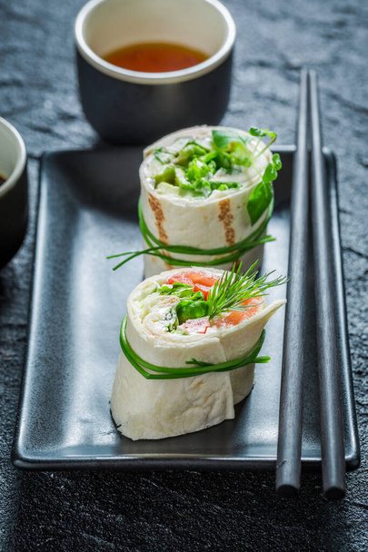 Unique and tasty tortilla with salmon, cheese and vegetables on black plate - 写真・画像