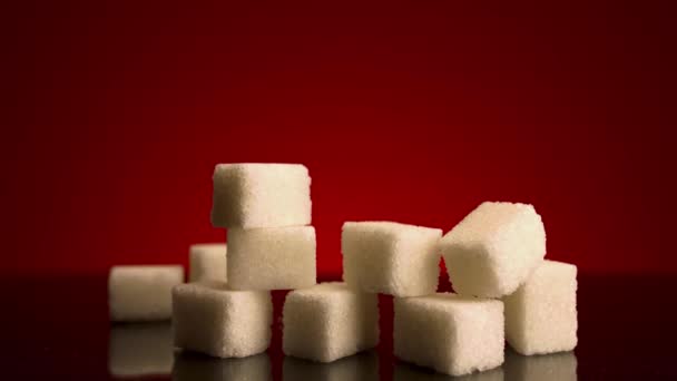Zuckerrohrwürfel isoliert auf rotem Hintergrund. Archivmaterial. Nahaufnahme einer Pyramide aus weißen Würfeln, Konzept von Süßigkeiten und Süßwaren. - Filmmaterial, Video