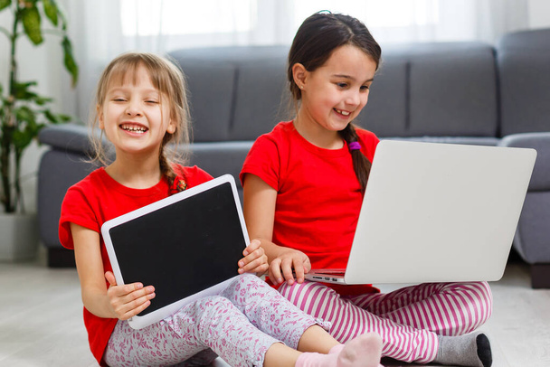 Kaksi pientä tyttöä istuu kannettavan tietokoneen edessä ja nauraa, lähikuva, positiiviset tunteet, viihdettä Internetissä lapsille - Valokuva, kuva