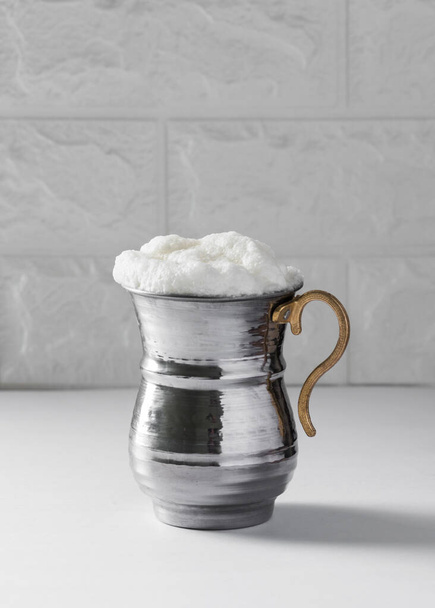 AYRAN. Traditional Turkish yoghurt drink with foam in silver metal cup. Buttermilk with white background - Photo, Image