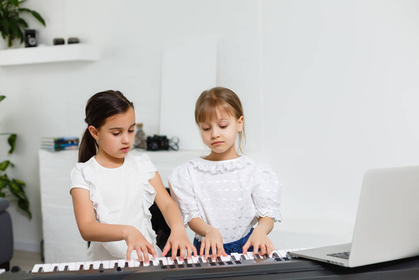 Hausunterricht über Musik für das Mädchen am Klavier. Die Idee von Aktivitäten für das Kind zu Hause während der Quarantäne. Musikkonzept - Foto, Bild