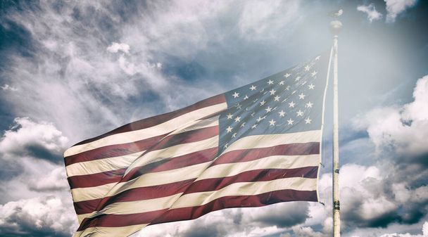 Цвета заката на фоне размахивающего красивым американским флагом. - Фото, изображение
