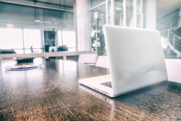 Laptop na stole nowoczesnego wnętrza sali konferencyjnej z widokiem na meble w świetle dziennym. - Zdjęcie, obraz