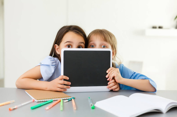 Учимся на дому, у детей домашней школы. Маленькие дети учатся онлайн-обучению дома с помощью ноутбука. Концепция карантина и социального дистанцирования. - Фото, изображение