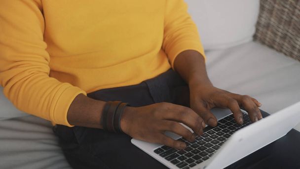 Close up, black man using laptop indoors - 写真・画像
