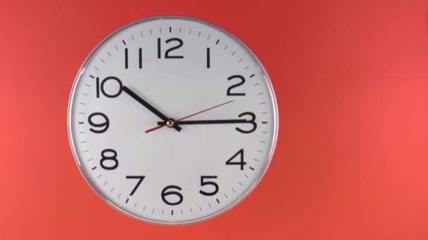 White wall clock with black numbers starting time 10.00 am or pm, on orange background, Time lapse 90 minutes in fast motion, copy space - Footage, Video