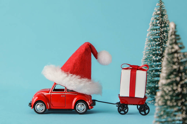Piros autó szállít karácsonyi vagy újévi ajándékokat a kék háttér. Karácsonyi ünnepi koncepció - Fotó, kép