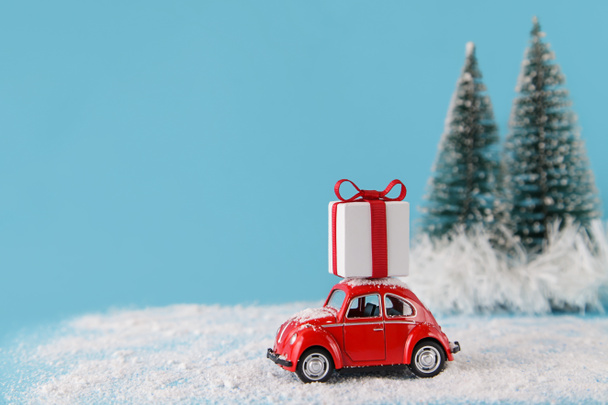 Czerwony samochód dostarcza pudełko z prezentami. Koncepcja świąt Bożego Narodzenia - Zdjęcie, obraz