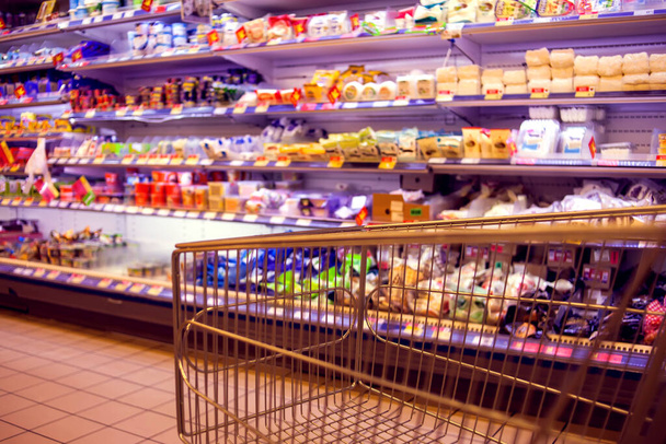 Αφηρημένη θολή φωτογραφία του καταστήματος με άδειο τρόλεϊ τροφίμων σε ένα σούπερ μάρκετ - Φωτογραφία, εικόνα
