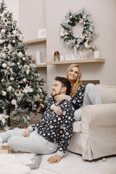 Cute couple at home near christmas tree - 写真・画像