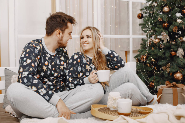 Cute couple at home near christmas tree - Foto, afbeelding