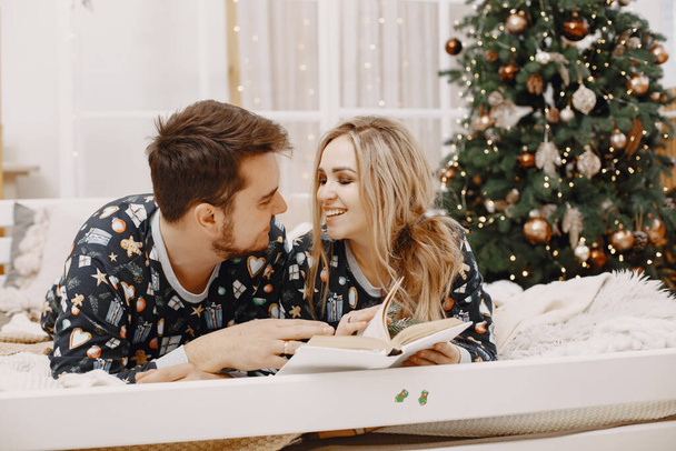 Cute couple at home near christmas tree - 写真・画像