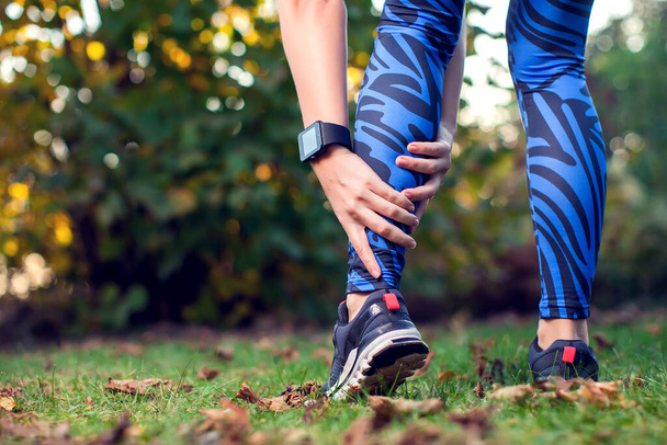 A női futó kint tartja a sérült lábát. Sport, orvostudomány és emberek koncepciója - Fotó, kép