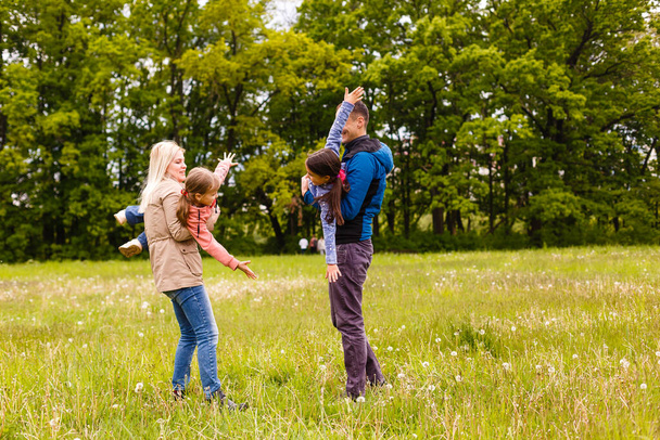 jong gezin lopen door een groen veld - Foto, afbeelding