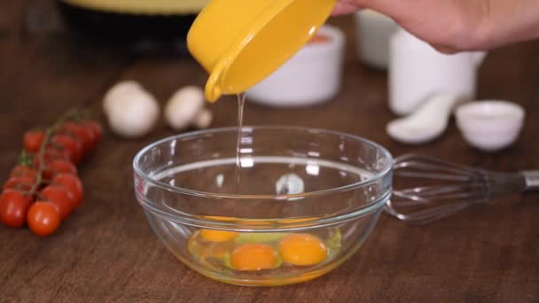 Ανακατεύοντας τρία φρέσκα ωμά αυγά κοτόπουλου σε ένα γυάλινο μπολ. - Πλάνα, βίντεο