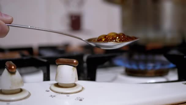Мужчина-наркоман готовит героин в ложке за газовой плитой дома - Кадры, видео