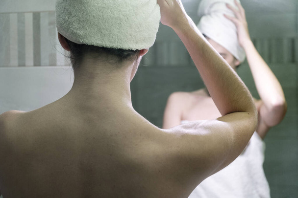 Młoda kobieta suszy włosy i ciało ręcznikami po prysznicu i pielęgnacji ciała przed lustrem w łazience - Zdjęcie, obraz