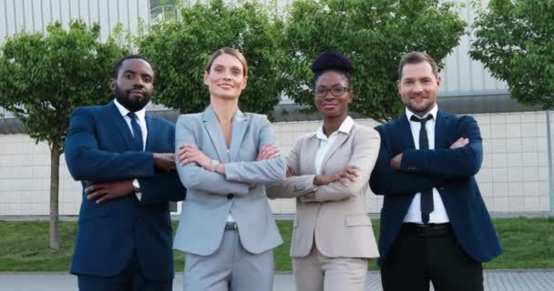 Portret van gemengde rassen jonge twee zakenmannen en zakenvrouwen staan buiten, poseren voor de camera, glimlachen en kruisen handen in de voorkant. Succesvol multi-etnisch team van zakenpartners. - Video
