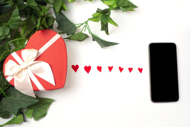 red paper hearts connect smartphone and gift. Concept of online Dating, love and relationships in quarantine and Covid-19. SValentines day - Foto, Imagem