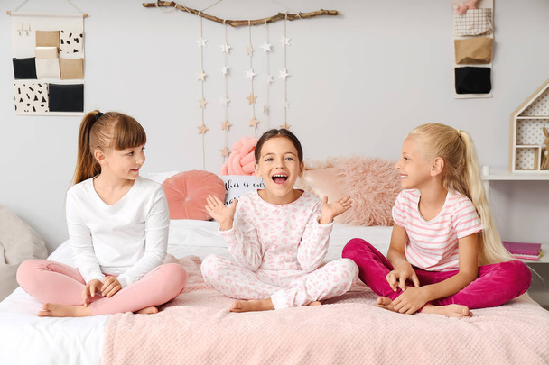 Evde pijamalarıyla yatakta oturan tatlı küçük kızlar. - Fotoğraf, Görsel