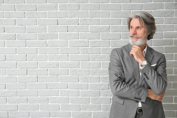 Mature man in formal suit on brick background - Photo, Image