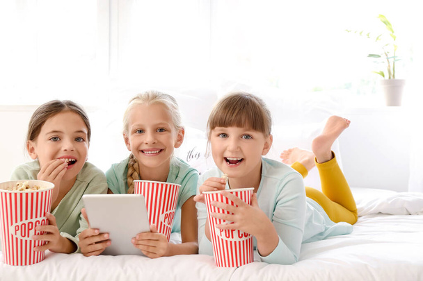 Cute little girls with tablet computer and popcorn at home - Φωτογραφία, εικόνα