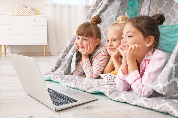 Aranyos kislányok fekszenek wigwam és néz rajzfilmeket laptopon - Fotó, kép