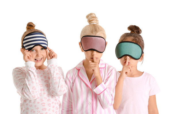 Schattige kleine meisjes in pyjama 's en slaap maskers op witte achtergrond - Foto, afbeelding