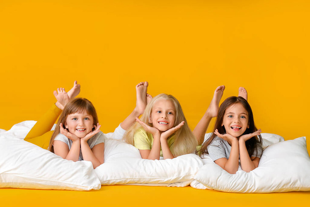 Nette kleine Mädchen mit Kissen auf farbigem Hintergrund - Foto, Bild