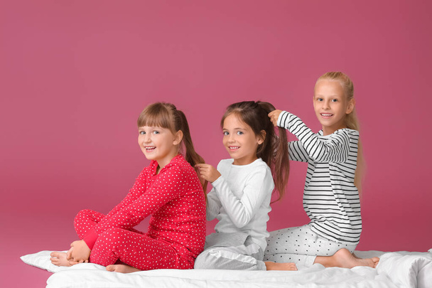 Cute little girls making braids on color background - Fotografie, Obrázek