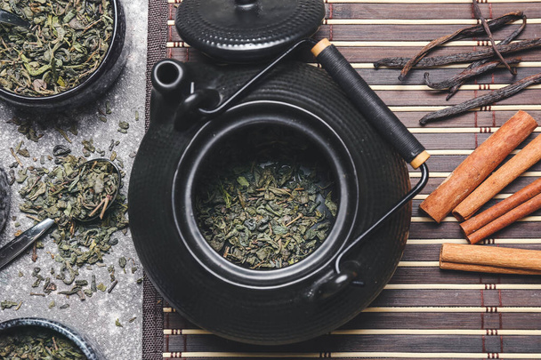 Teiera con tè verde secco e cannella su sfondo scuro - Foto, immagini