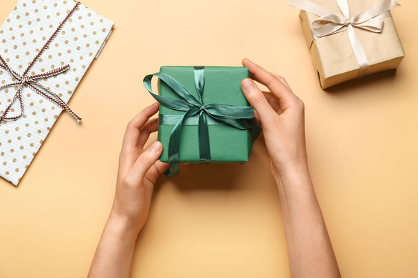 Hands with gift box on color background - Фото, изображение
