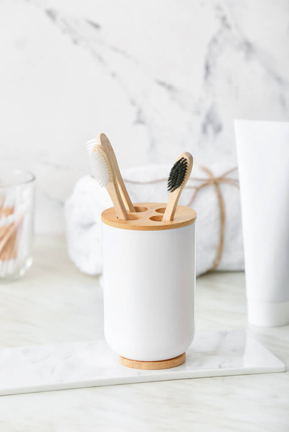 Holder with wooden toothbrushes on table in bathroom - Foto, Imagem