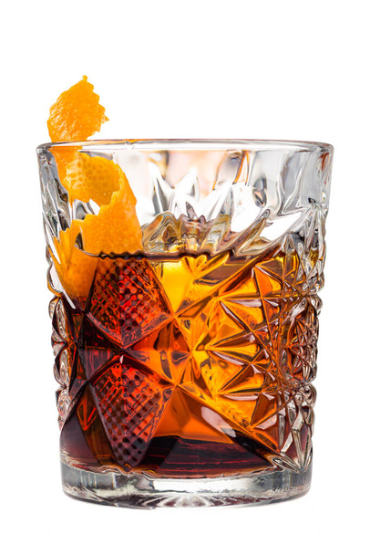Glass of Boulevardier cocktail with big ice cube and orange zest, classic cocktail Boozy Boulevardier with Orange and Vermouth isolated on white background - 写真・画像