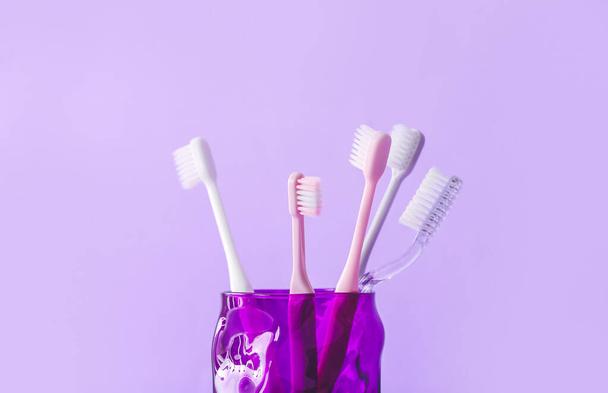 Soporte con cepillos de dientes sobre fondo de color - Foto, imagen