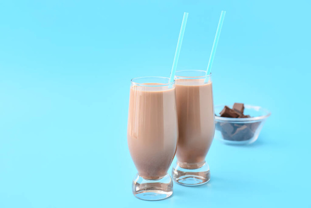 Стаканы вкусного шоколадного молока на цветном фоне - Фото, изображение
