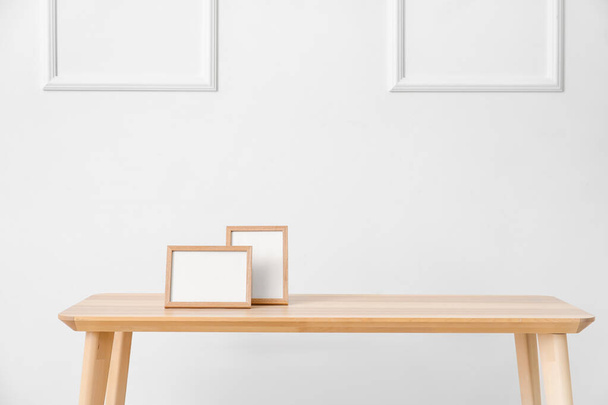 Elegante tavolo con cornici fotografiche vuote vicino alla parete luminosa in camera - Foto, immagini