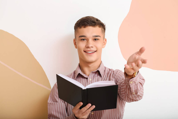 Teenage boy with book on color background - Foto, afbeelding