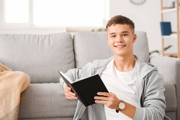 Teenage boy reading book at home - Фото, изображение