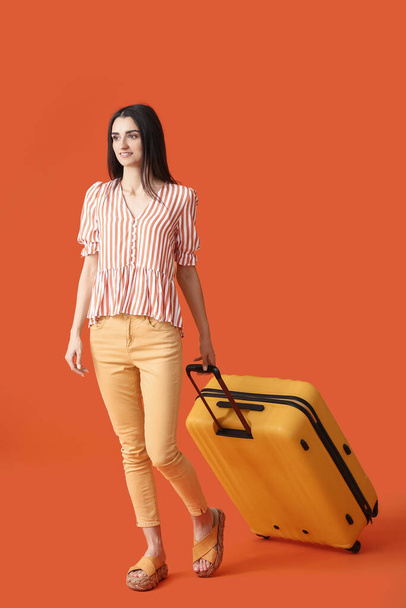 Young woman with suitcase on color background - Foto, immagini