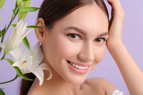Beautiful young woman with fresh lilies on color background - Foto, imagen