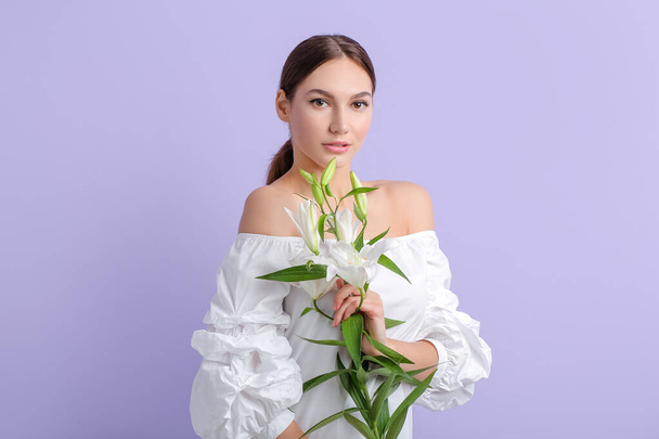 Beautiful young woman with fresh lilies on color background - Foto, Bild