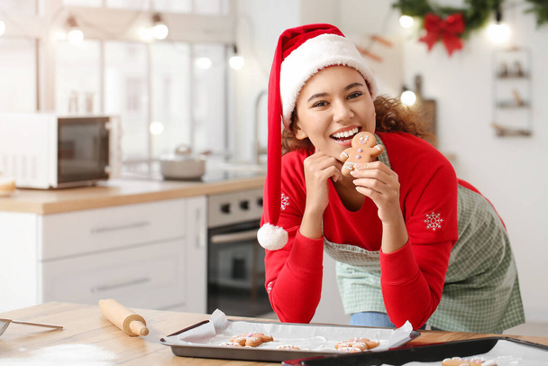 Jeune femme avec de savoureux biscuits maison au pain d'épice dans la cuisine la veille de Noël - Photo, image