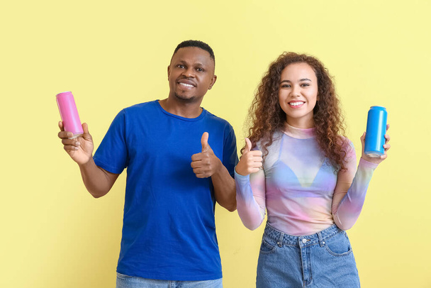 Afro-amerikanisches Paar mit Soda zeigt Daumen nach oben auf farbigem Hintergrund - Foto, Bild