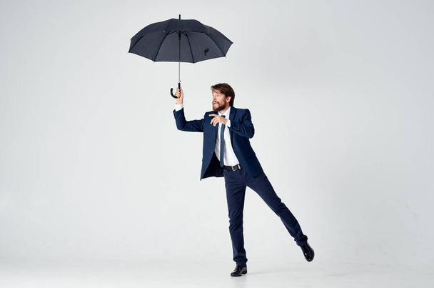 Джентльмен с открытым зонтиком в темном костюме, наклоненном в сторону - Фото, изображение