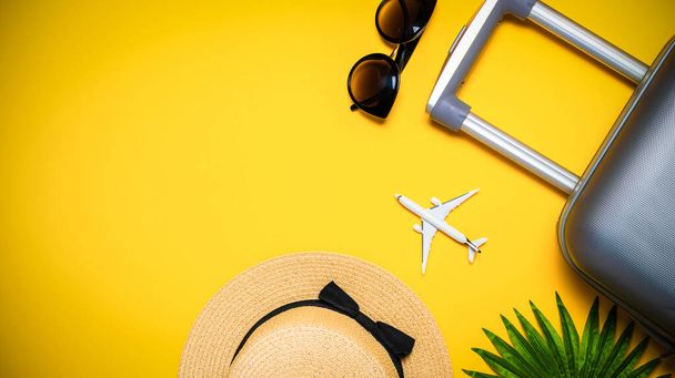 Zomer vakantie poster. Dames accessoires reiziger: koffer, wit vliegtuig, zonnebril op gele achtergrond met lege ruimte voor tekst. Zomervakantie en product reclame concept - Foto, afbeelding