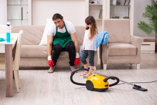 Young male contractor cleaning the house with his small daughter - 写真・画像