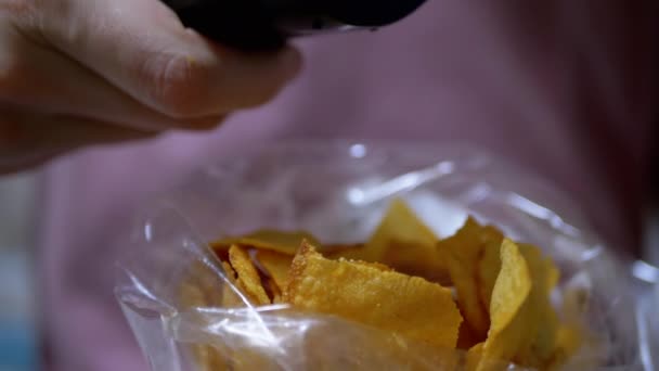 Vrouwelijke Holding Packet van Aardappel Chips Druk op knoppen met vingers op TV Remote - Video